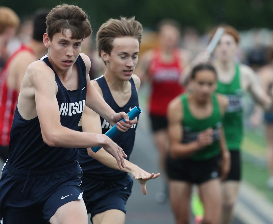 Hudson's Nathan Henderson, left, gets the baton from Tyler Ginther in the 3,200-meter relay during the Suburban League National Conference track and field championships at Twinsburg, Tuesday, May 7, 2024.