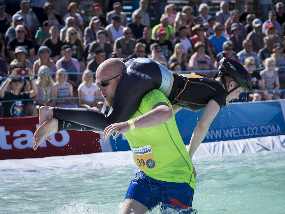 A man runs through the water while carrying a woman during the Wife Carrying World Championships in Sonkajaervi, Finland, in 2017.