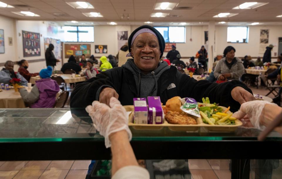 Theresa Davis grabs a platter full of food inside Capuchin Soup Kitchen in Detroit on Thursday, Dec. 7, 2023. The Capuchin Soup Kitchen is close to a century old and has served the Detroit community since 1929.