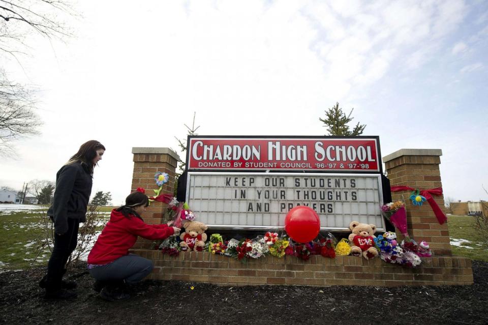 PHOTO: Maria Cochran and Andressa Green of Chardon place flowers on the sign outside Chardon High School in Chardon, Ohio, Feb. 28, 2012. (Jeff Swensen/Getty Images, FILE)