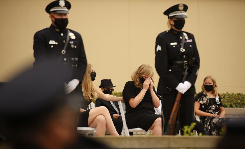 LOS ANGELES, CA - AUGUST 06: Megan Flynn, right, domestic partner of LAPD Officer Valentin Martinez who is pregnant with twins is comforted by her sister Shannon Bevers, during the funeral of Officer Martinez, the agency's first sworn employee to die of complications from the COVID-19. The social distance memory service was held at Forest Lawn Hollywood Hills' Hall of Liberty this morning. Martinez was a 13-year veteran of the department and is presumed to have contacted the virus on duty. He was 45 when he died on July 24, 2020, leaving behind his mother, Maria Martinez, his siblings and his domestic partner, Megan Flynn, who is pregnant with their twins. Los Angeles on Thursday, Aug. 6, 2020 in Los Angeles, CA. (Al Seib / Los Angeles Times)