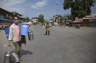 A Kashmiri milkman walks past a paramilitary soldier during curfew in Srinagar, Indian controlled Kashmir, Tuesday, Aug. 4, 2020. Authorities clamped a curfew in many parts of Indian-controlled Kashmir on Tuesday, a day ahead of the first anniversary of India’s controversial decision to revoke the disputed region’s semi-autonomy. Shahid Iqbal Choudhary, a civil administrator, said the security lockdown was clamped in the region’s main city of Srinagar in view of information about protests planned by anti-India groups to mark Aug. 5 as “black day." (AP Photo/Mukhtar Khan)