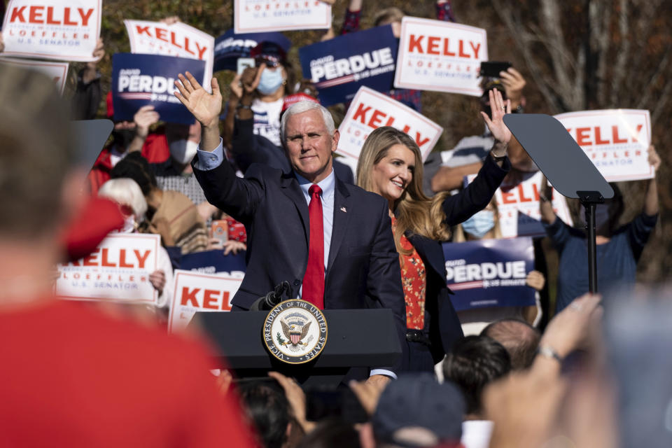 Vice President Mike Pence and Kelly Loeffler wave to the crowd during a Defend the Majority Rally, Friday, Nov. 20, 2020 in Canton, Ga. U.S. Sen. Kelly Loeffler waves behind Pence. (AP Photo/Ben Gray)