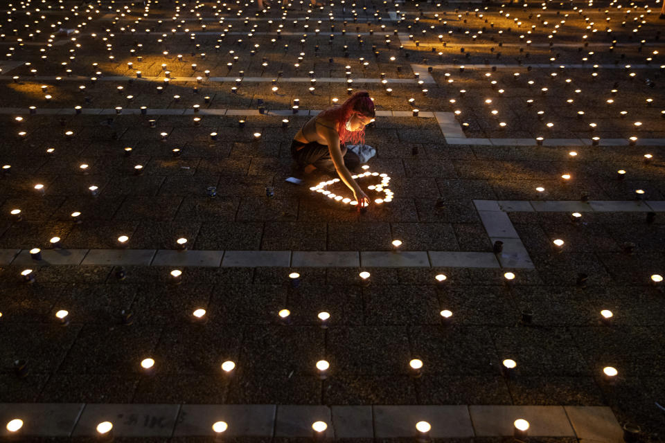 A woman lights memorial candles on the 25th anniversary of the assassination of Israeli Prime Minister Yitzhak Rabin, at Rabin Square, Tel Aviv, Israel, Thursday, Oct. 29, 2020. (AP Photo/Oded Balilty)