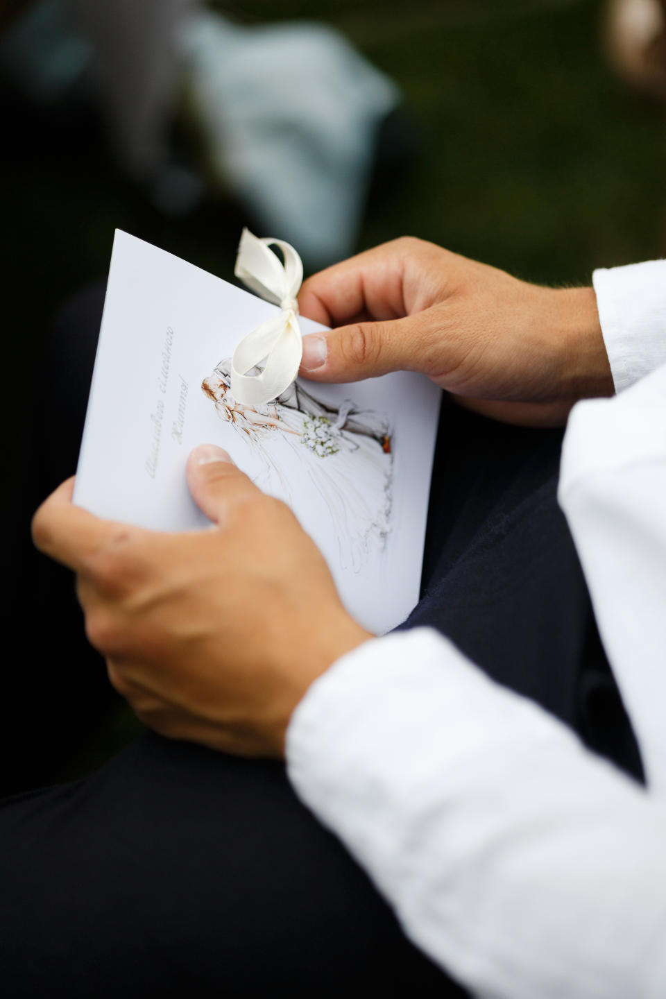 A man's hands hold a wedding card containing his wedding vows.