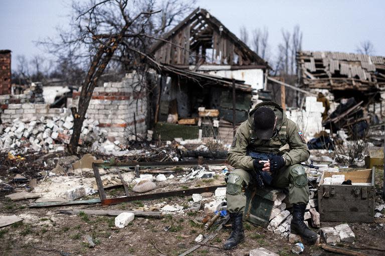 A pro-Russian rebel sits in front of destroyed houses in the village of Lohvynove, near the eastern Ukrainian town of Debaltseve, on March 26, 2015
