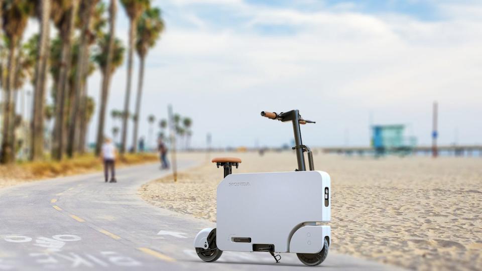 a scooter parked on a road with a beach and trees in the background