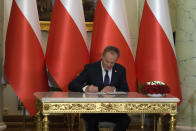 The new Polish Prime Minister Donald Tusk signs an oath at the presidential palace in Warsaw, Poland, Wednesday, Dec. 13, 2023. Donald Tusk was sworn in by the president in a ceremony where each of his ministers were also taking the oath of office. (AP Photo/Czarek Sokolowski)