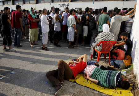 Syrian refugees line-up as others sleep on the floor during a registration procedure at the national stadium of the Greek island of Kos August 11, 2015. REUTERS/ Yannis Behrakis