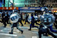 Protestors face police chase protesters during a protest in Nathan road, Hong Kong on Friday, Sept. 6, 2019. The ratings agency Fitch on Friday cut Hong Kong's credit rating and warned that conflict with anti-government protesters was hurting the image of its business climate. (AP Photo/Vincent Yu)