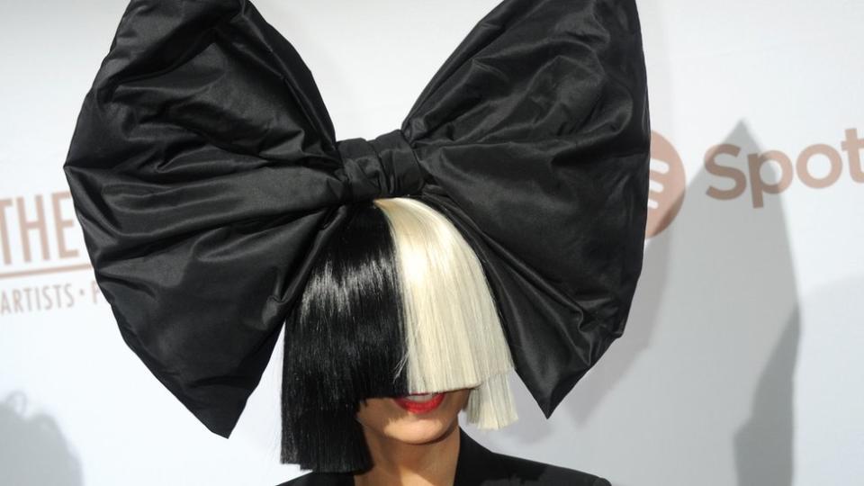 Sia con el rostro cubierto por pelo negro y rubio.