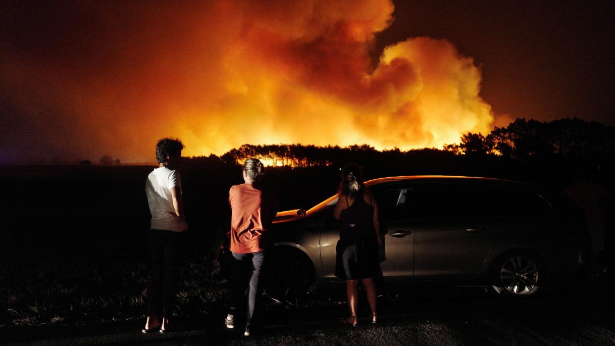 People watch a wildfire in Aljesur, Portugal, 7 August (REUTERS)