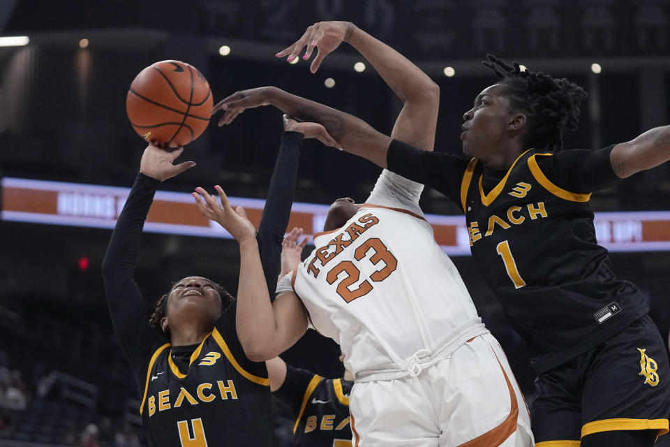 Texas forward Aaliyah Moore (23) battles Long Beach State guard Cheyenne Givens (4) and guard Lovely Sonnier (1) for a rebound during the second half of an NCAA college basketball game in Austin, Texas, Wednesday, Dec. 6, 2023. (AP Photo/Eric Gay)