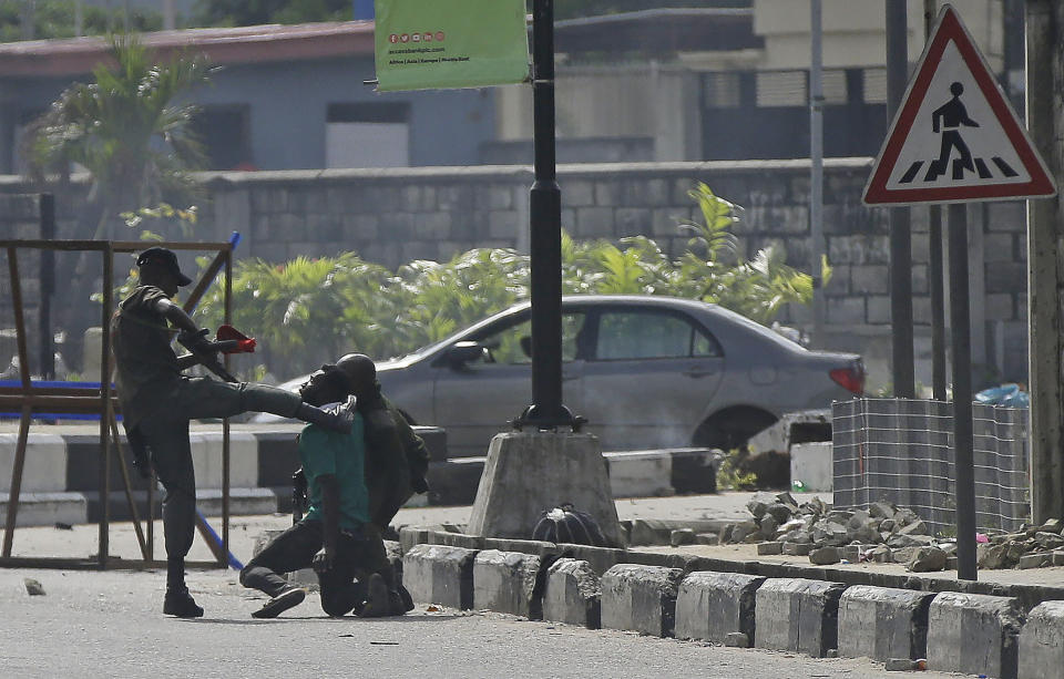 Police officers detain a protester at the Lekki toll gate in Lagos, Nigeria, Wednesday Oct. 21, 2020. After 13 days of protests against alleged police brutality, authorities have imposed a 24-hour curfew in Lagos, Nigeria's largest city, as moves are made to stop growing violence.( AP Photo/Sunday Alamba)