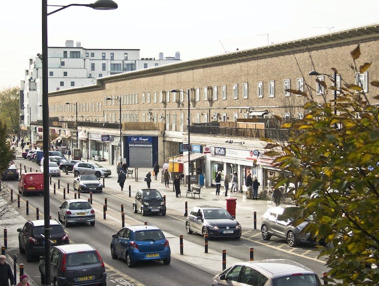 A long building with cars and shops.