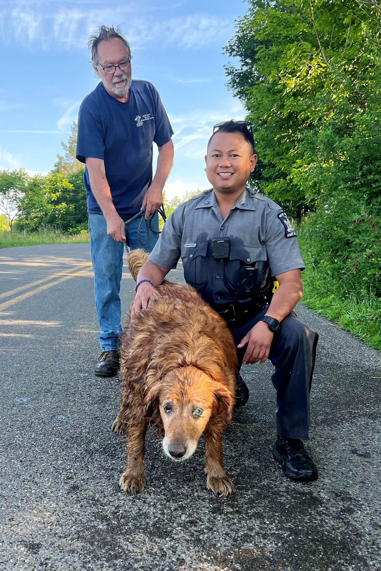 In this image provided by the New York State Police, Trooper Jimmy Rasaphone, right, poses for a photo with 13-year-old golden retriever Lilah, and her owner Rudy Fuehrer, after the trooper rescued her from a culvert pipe in Conklin, NY., on Sunday, June 26, 2022. 