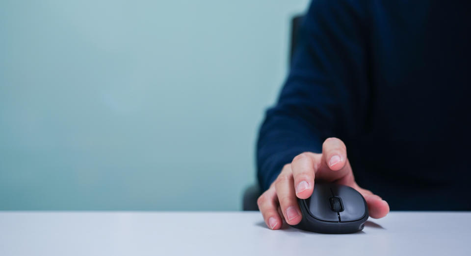 close up employee man hand using mouse cursor for scrolling web page or working on computer program at desktop in office  concept