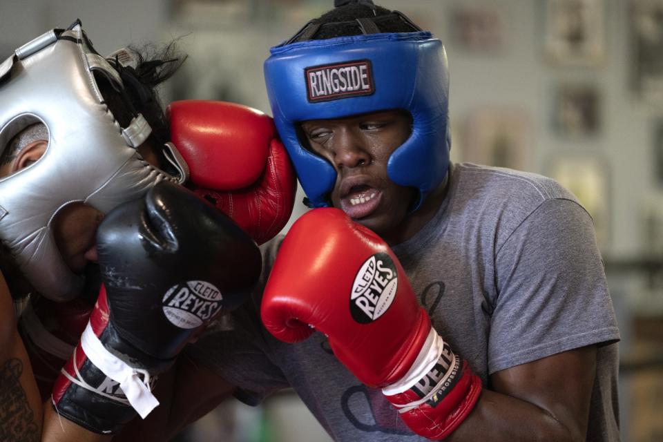 Theon Davis, 21, right, spars with another boxer as he trains for his 176-pound Chicago Golden Gloves tournament boxing match at Garfield Park Boxing Wednesday, March 29, 2023, in Chicago. Davis started training for boxing to get in shape to play college football, but he didn’t have the grades for that. When he found out he was going to be a father, he decided to stay home. Family, work and boxing keep him busy. (AP Photo/Erin Hooley)