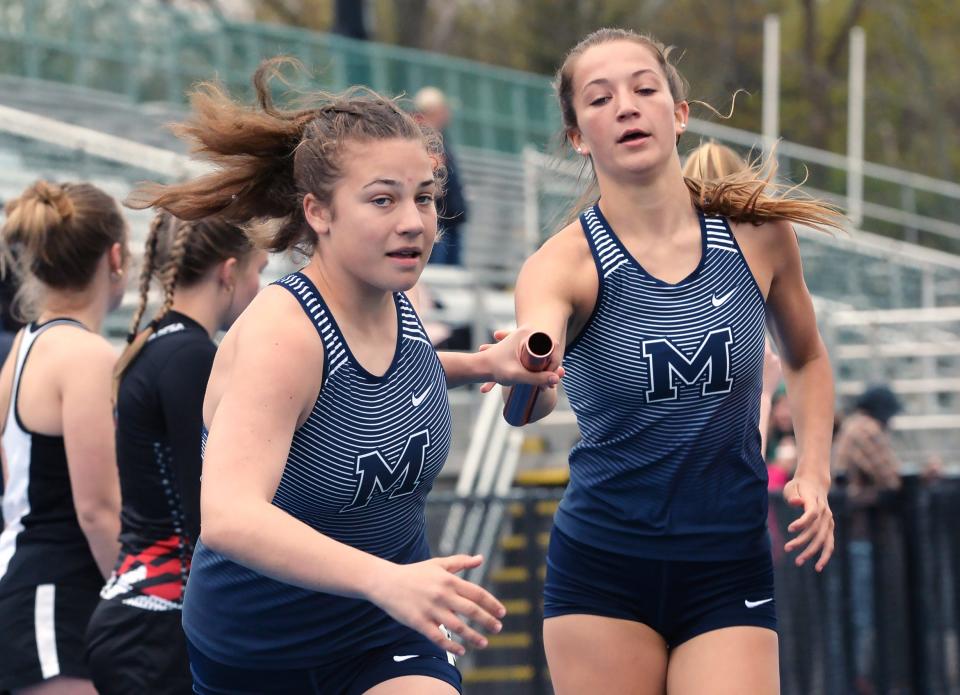 McDowell High School's Grace Faulkner, left, takes the baton from teammate Hayden Palmer during the girls 3,200-meter relay at Joe Sanford's McDowell Track and Field Invitational.