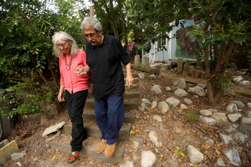 LOS ANGELES, CA - JUNE 13, 2023 - Mannie Rezende, 71, suffering from Alzheimer's, walks with his wife Rose, 69, in the backyard of their home in Shadow Hills on June 13, 2023. Rose continues to take care of her husband's needs as his memory declines. "It's hard because we raised a special needs child. I didn't know I'd have to do it again," Rose said about taking care of her husband. "It's frustrating. Not awful, but frustrating," Rezende said about his memory loss. (Genaro Molina / Los Angeles Times)