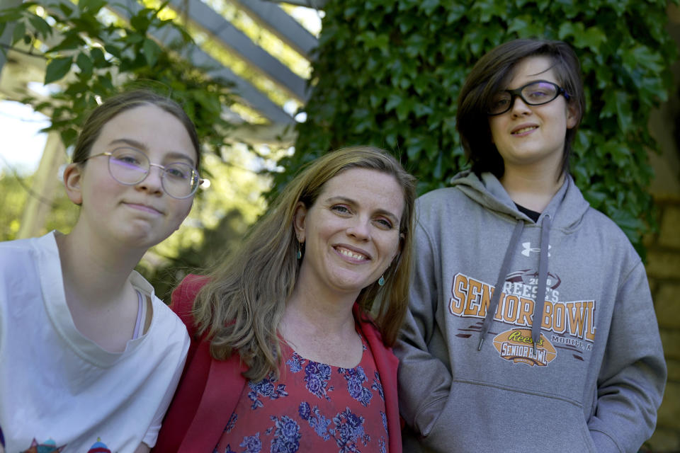 Heather Ousley sits with her older children Elliannah, 15, and Samuel, 13, in front of their home in Merriam, Kan, Tuesday, May 4, 2021. Ousley was thrilled when she heard the FDA was expected to authorize Pfizer's COVID-19 vaccine for youngsters ages 12 to 15 and was hoping to get her kids vaccinated as soon as she can. (AP Photo/Charlie Riedel)