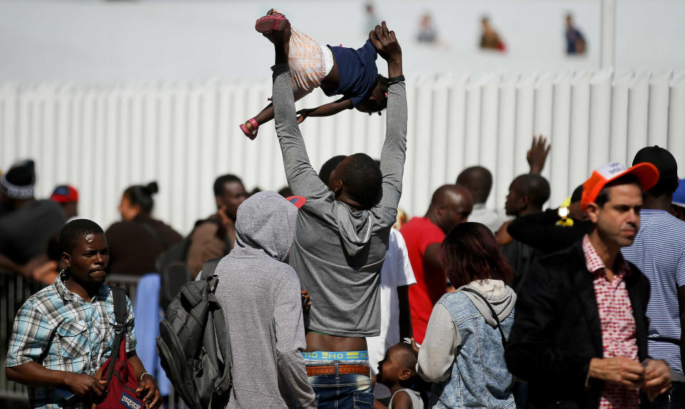 A migrant plays with his little girl as they wait to be attended to apply for asylum in the United States, at the border in Tijuana, Mexico, Sunday, June 9, 2019. The mechanism that allows the U.S. to send migrants seeking asylum back to Mexico to await resolution of their process has been running in Tijuana since January. (AP Photo/Eduardo Verdugo)