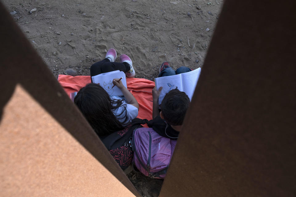 Children part of a group of more than 50 asylum seekers, mainly from South America, draw as their group wait for US authorities process them next to the US-Mexico Border wall seen from Tijuana, Baja California state, Mexico on September, 2022. / Credit: GUILLERMO ARIAS/AFP via Getty Images