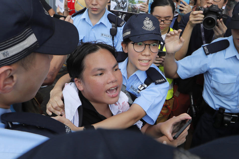 A pro-democracy protester is stopped by police officers as she argues with pro-China's supporters during a rally outside Legislative Council Complex in Hong Kong, Sunday, June 30, 2019. Pro-China's supporters rallied in support of the police at Tamar Park (AP Photo/Kin Cheung)