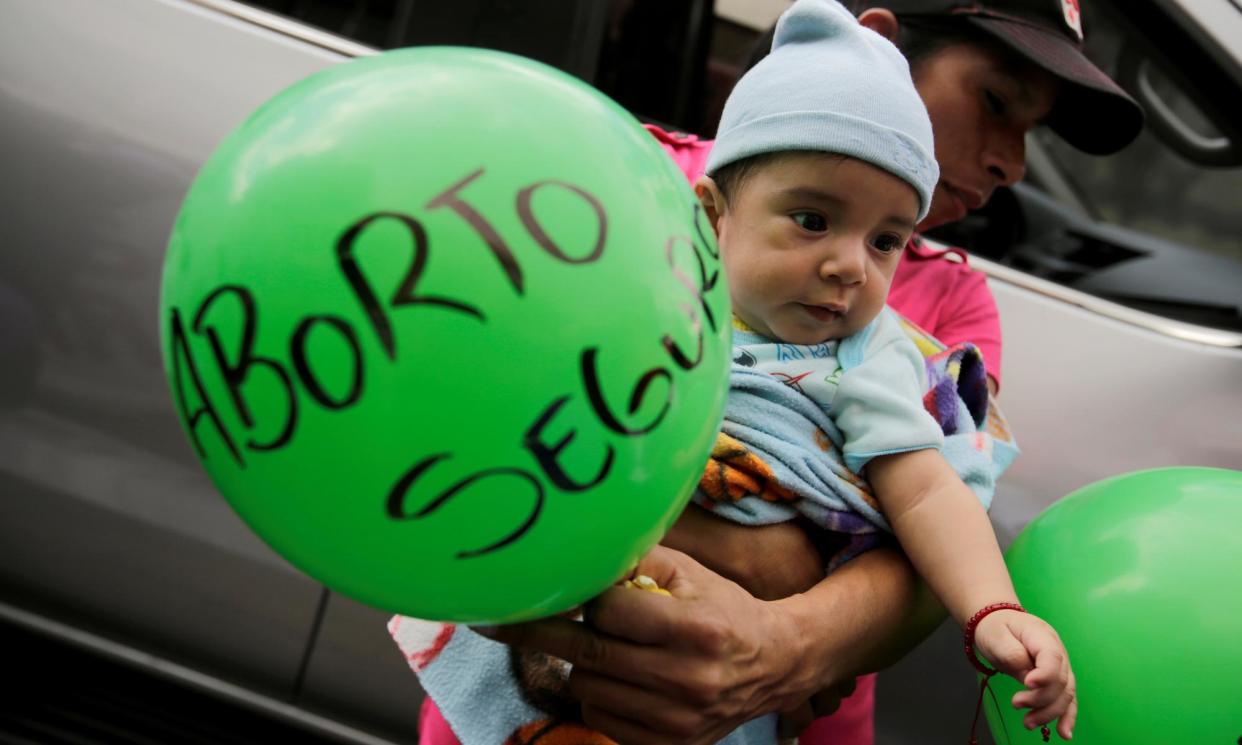 <span>A man carries his son during a protest to mark International Women’s Day outside the public prosecutor’s office in Tegucigalpa, Honduras.</span><span>Photograph: Jorge Cabrera/Reuters</span>