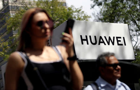 FILE PHOTO: People walk past a Huawei company logo at a bus stop in Mexico City, Mexico February 22, 2019. Picture taken February 22, 2019. REUTERS/Daniel Becerril/File Photo