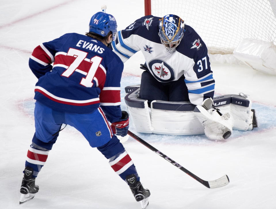 Winnipeg Jets goaltender Connor Hellebuyck stops Montreal Canadiens' Jake Evans during second-period NHL hockey game action in Montreal, Saturday, April 10, 2021. (Graham Hughes/The Canadian Press via AP)