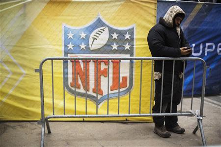 A worker looks at his phone in front of a banner on Broadway as preparations continue for Super Bowl XLVIII in New York January 28, 2014. REUTERS/Lucas Jackson