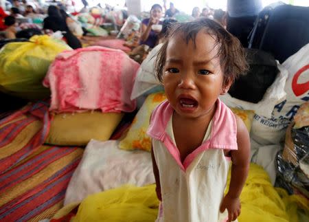 A girl cries next to other residents taking shelter at a basketball court after they were evacuated at the height of Typhoon Kalmaegi in Marikina, Metro Manila September 15, 2014. REUTERS/Erik De Castro