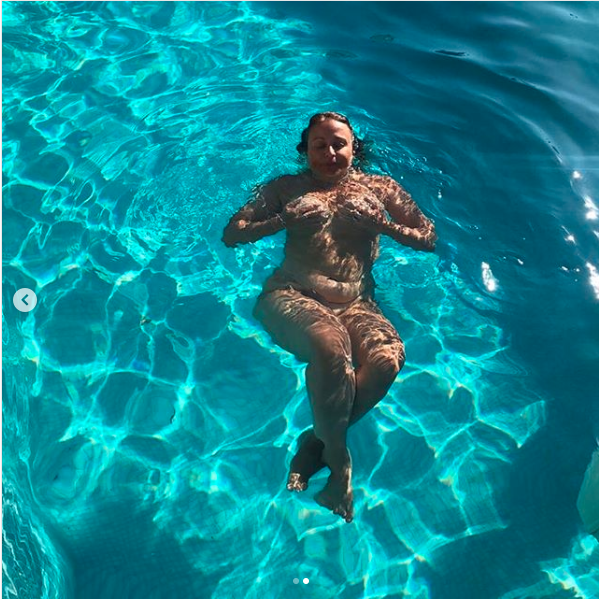 Nadia Sawalha swimming naked while holding her breasts