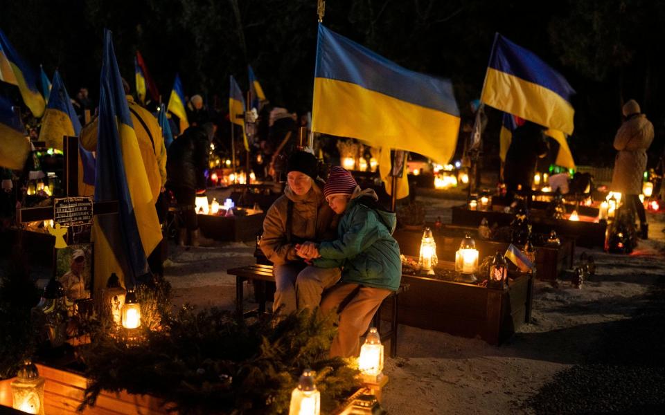 Olesia and her daughter Uliana sits next to the grave of her husband Ihor Marchenko at Lviv cemetery, western Ukraine, - AP Photo