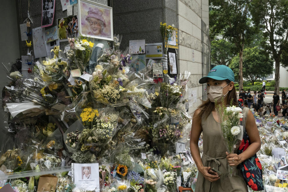 A woman lays flowers as a tribute outside the British Consulate in Hong Kong, Friday, Sept. 16, 2022. In Britain, Thousands of mourners waited for hours Thursday in a line that stretched for almost 5 miles (8 kilometers) across London for the chance to spend a few minutes filing past Queen Elizabeth II's coffin while she lies in state. (AP Photo/Anthony Kwan)