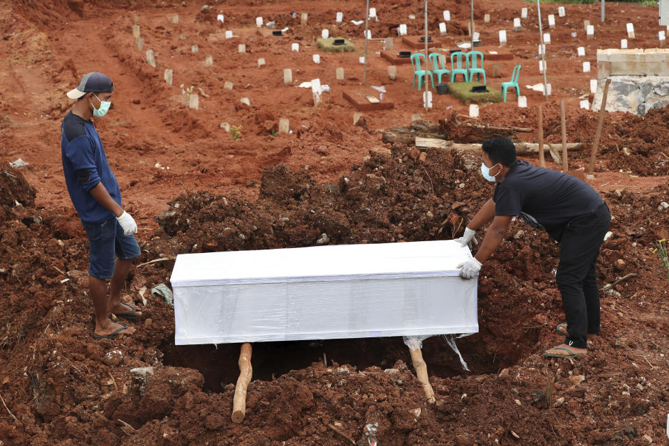 Workers prepare a coffin for burial at the special section of Jombang cemetery which was opened to accommodate the surge in deaths during coronavirus outbreak, in Tangerang, Indonesia, Tuesday, Jan. 26, 2021. Indonesia has reported more cases of the virus than any other countries in Southeast Asia. (AP Photo/Tatan Syuflana)