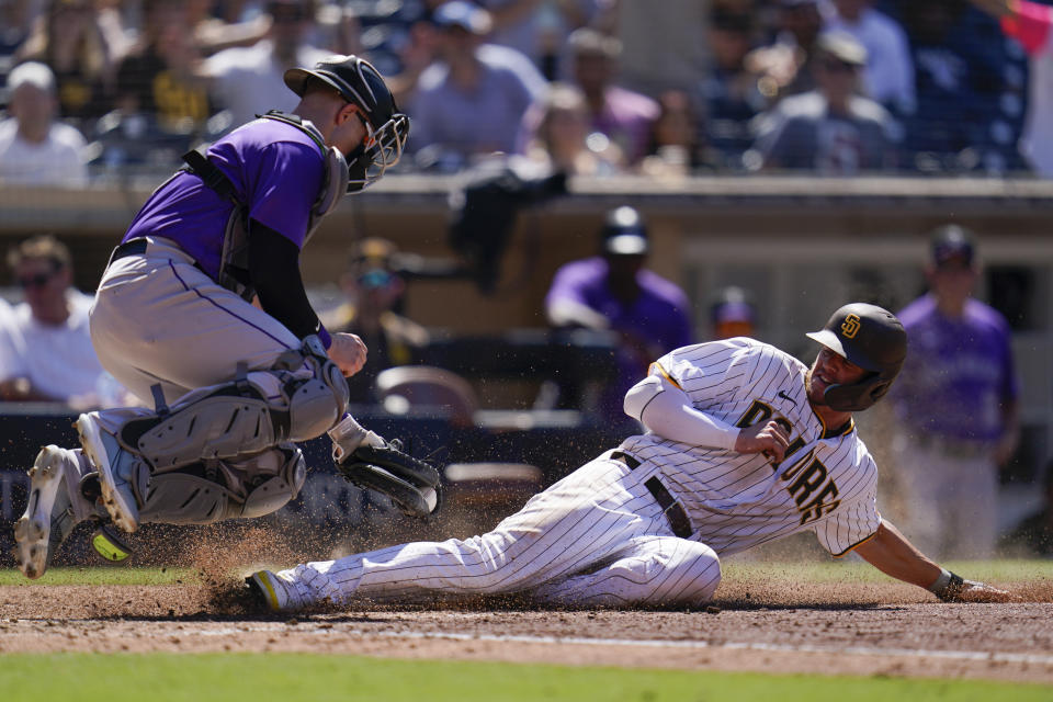 San Diego Padres' Wil Myers, right, slides safely to home, scoring off an RBI-single by Ha-Seong Kim, as Colorado Rockies catcher Brian Serven is late with the tag during the fifth inning of the first baseball game of a doubleheader Tuesday, Aug. 2, 2022, in San Diego. (AP Photo/Gregory Bull)
