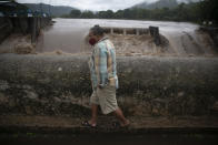 A man walks on a bridge over Los Esclavos river during tropical storm Amanda in Cuilapa, eastern Guatemala, Sunday, May 31, 2020. The first tropical storm of the Eastern Pacific season drenched parts of Central America on Sunday and officials in El Salvador said at least seven people had died in flooding. (AP Photo/Moises Castillo)