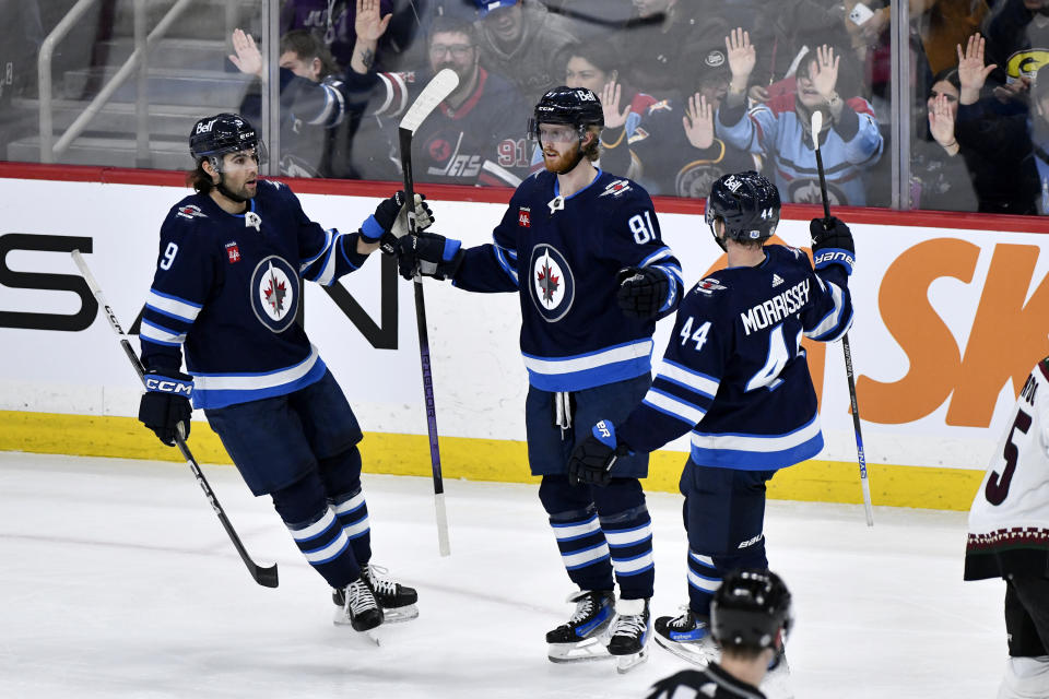 Winnipeg Jets left wing Kyle Connor (81) celebrates his goal against the Arizona Coyotes with teammates Alex Iafallo (9) and Josh Morrissey (44) during the first period of an NHL hockey game in Winnipeg, Manitoba on Sunday, Feb. 25, 2024. (Fred Greenslade/The Canadian Press via AP)