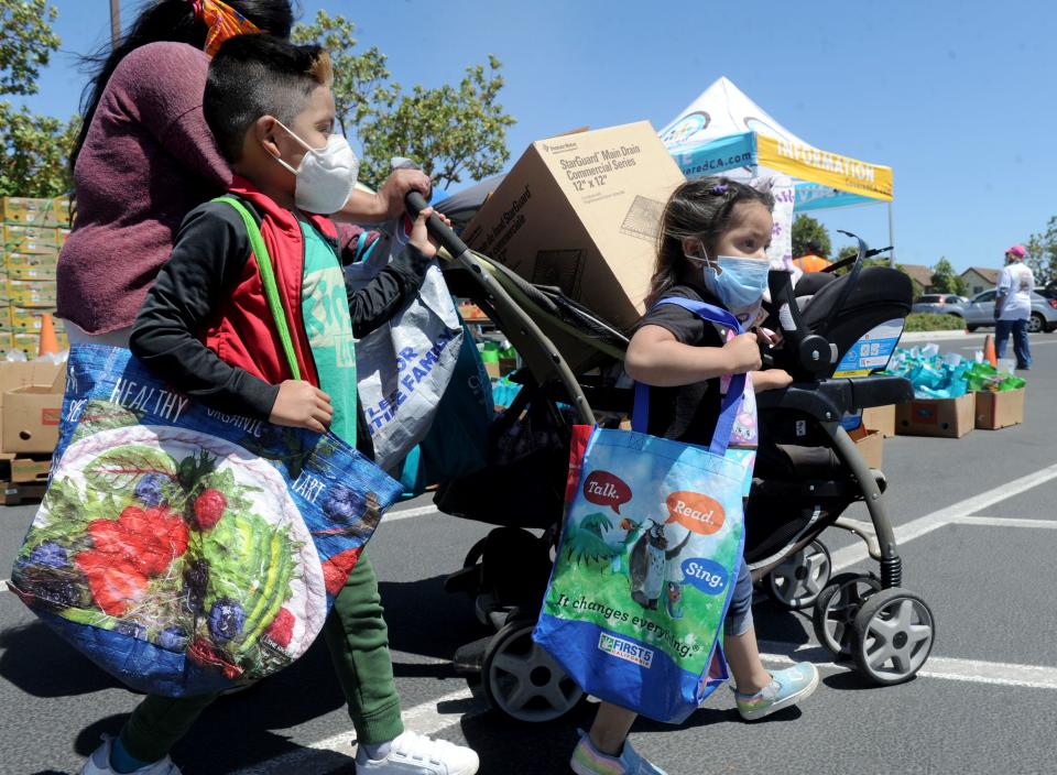 Gilberto Gonzalez, 6, left, and his sister Viviana Gonzalez, 4, help their mother Rosalba Gonzalez carry food at the Feeding The Frontline event at Our Lady of Guadalupe in Oxnard on Saturday, June 13, 2020.