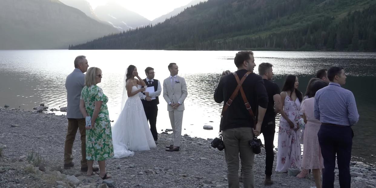 a screenshot of a wedding in Glacier National Park in which the people look shocked and all are facing away from the ceremony