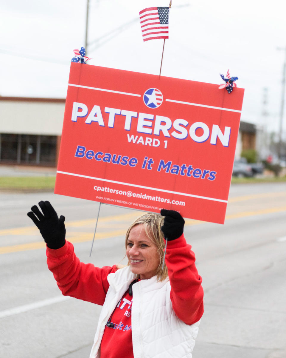Cheryl Patterson waves while holding a campaign sign. (Michael Noble Jr. for NBC News)