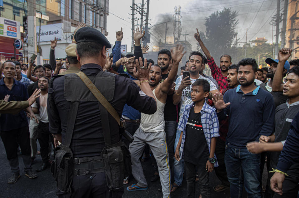 An Indian commando tries to stop as protesters block traffic during a shutdown protest against the Citizenship Amendment Bill (CAB) in Gauhati, India, Tuesday, Dec. 10, 2019. Opponents of legislation that would grant Indian citizenship to non-Muslim illegal migrants from Pakistan, Bangladesh and Afghanistan have enforced an 11-hour shutdown across India's northeastern region. (AP Photo/Anupam Nath)