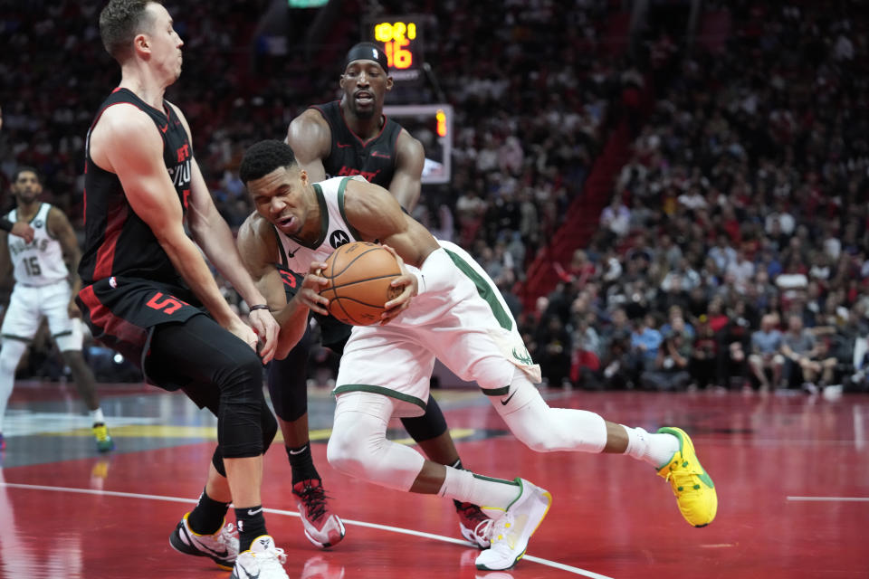 Milwaukee Bucks forward Giannis Antetokounmpo, center, collides with Miami Heat forward Duncan Robinson (55) as he drives past Robinson and center Bam Adebayo, rear, during the second half of an NBA basketball game, Tuesday, Nov. 28, 2023, in Miami. (AP Photo/Wilfredo Lee)