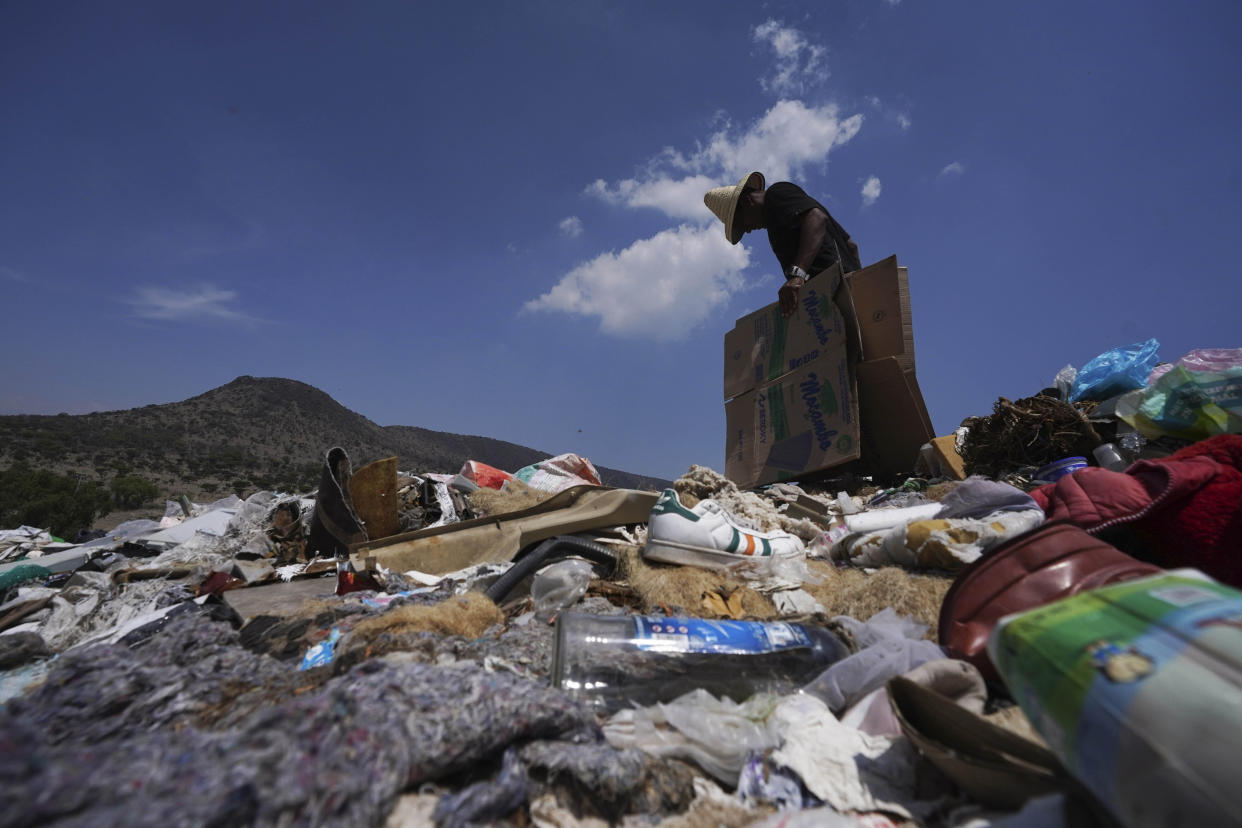 A migrant gathers pieces of cardboard to sleep on, in Huehuetoca, Mexico, Friday, May 12, 2023, while waiting to board a freight train heading north, the day after U.S. pandemic-related asylum restrictions called Title 42 were lifted. (AP Photo/Marco Ugarte)