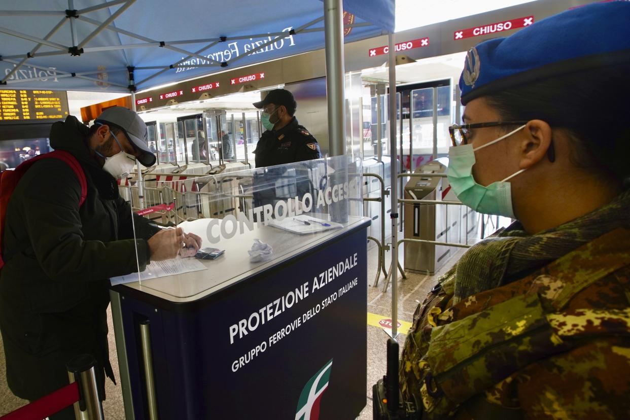 A traveler wears a mask as she fills out a form at a check point set up by border police inside Rome's Termini train station, on Tuesday, March 10, 2020.