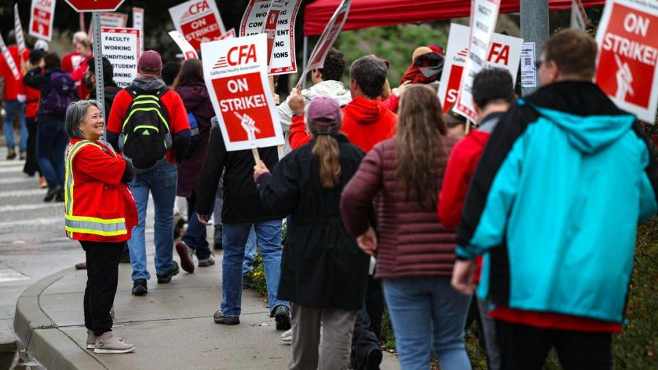 CFA-SLO President Lisa Kawamura, left, watches as striking Cal Poly faculty members picket at the corner of California Boulevard and Highland Drive in San Luis Obispo on Jan. 22, 2024.