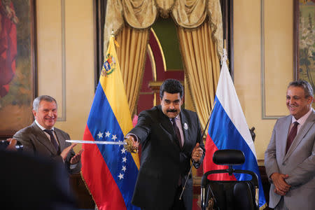 Foto de archivo. El presidente venezolano Nicolás Maduro sostiene una réplica de la espada del prócer nacional Simón Bolívar ante la mirada del jefe de Rosneft Igor Sechin y del ministro de Petróleo y presidente de PDVSA Eulogio del Pino durante la ceremonia de un acuerdo entre Rosneft y PDVSA en Caracas, Venezuela, 28 de julio, 2016. Palacio de Miraflores/Handout via REUTERS