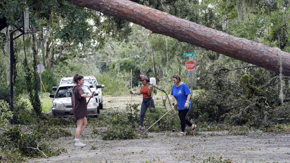 Desde la izquierda, los residentes Alana Hall, Kayci Carter y Tracy Hall retiran escombros dejados por el paso del huracán Idalia frente a su casa, el miércoles 30 de agosto de 2023, en Perry, Florida. (AP Foto/John Raoux)